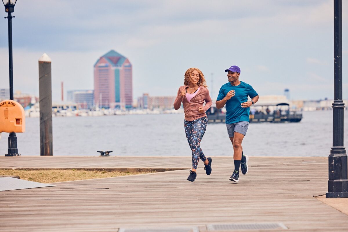 A black man and woman down a pier in front of the water
