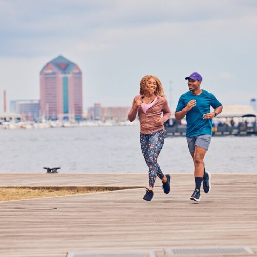 A black man and woman down a pier in front of the water