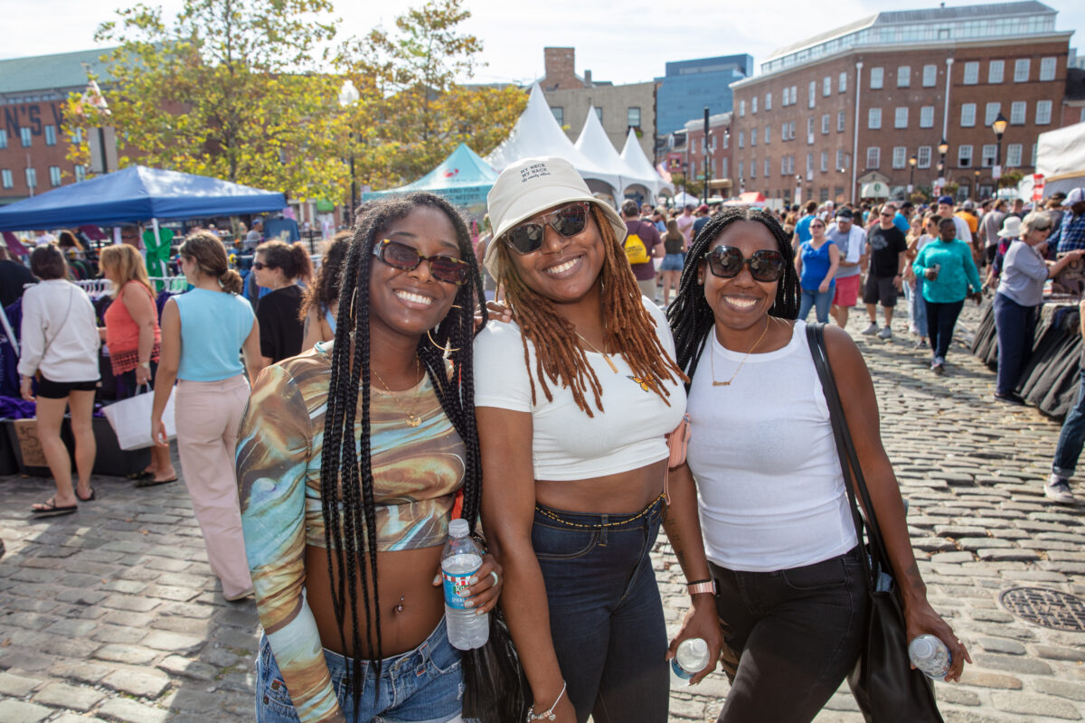 three women smile for a photo in Fell's Point