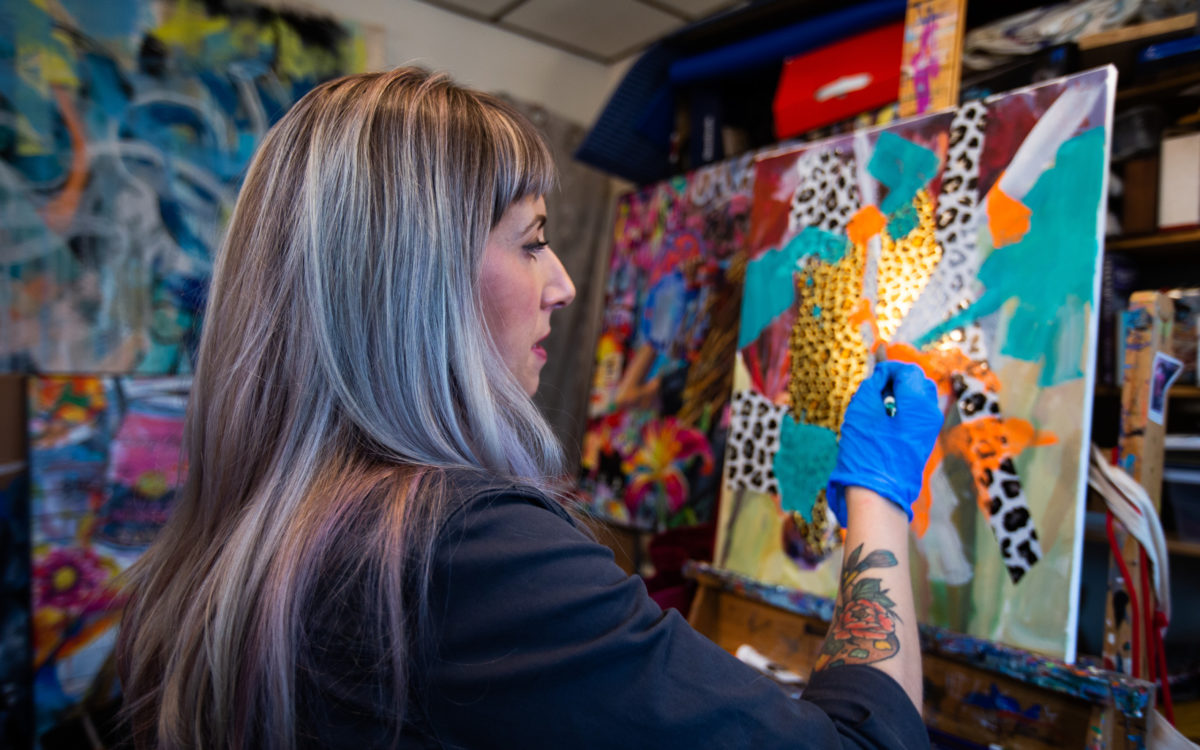 a woman works on a piece of art at Night Owl Gallery