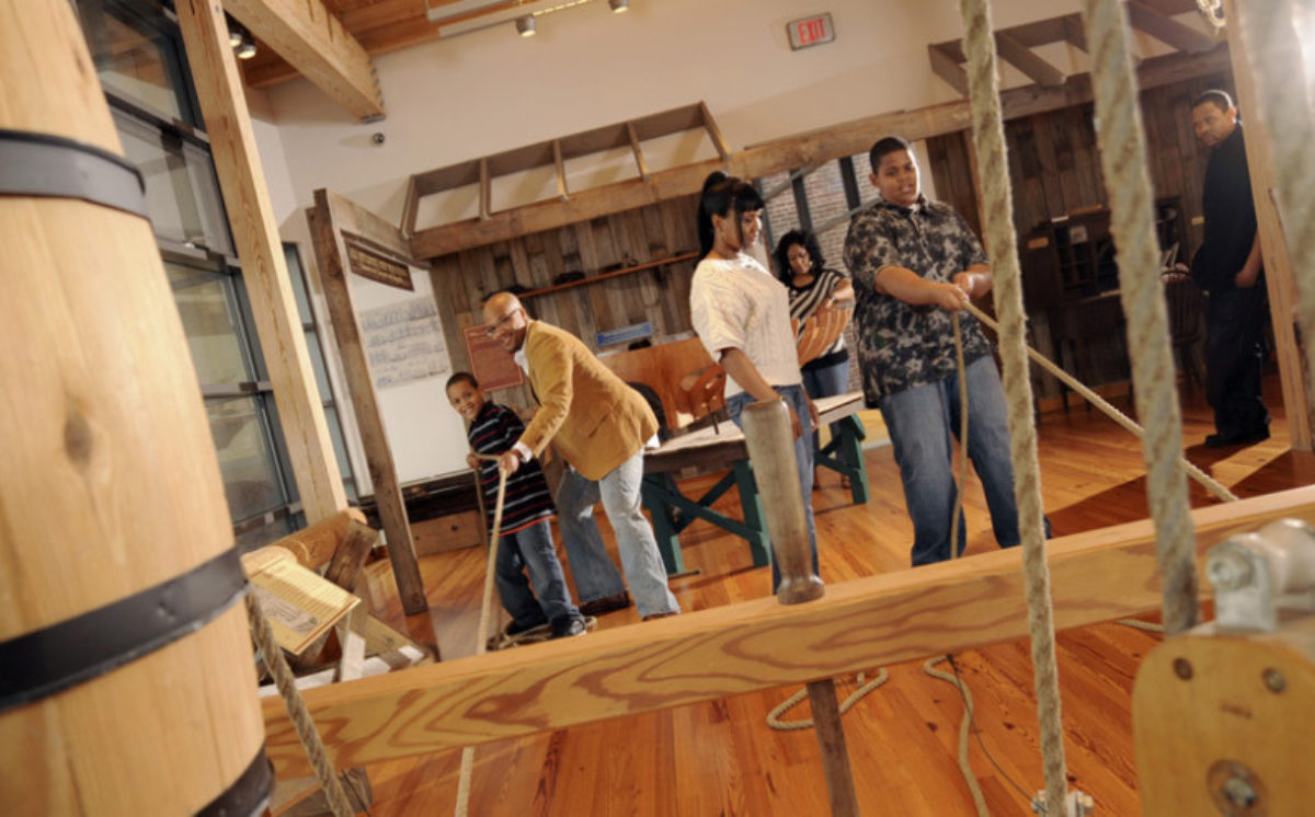 People interacting with an exhibit with ropes and barrels