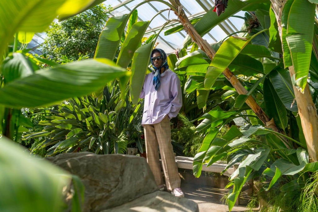 Jacob Marley photographed between plants from afar inside The Rawlings Conservatory in Baltimore.