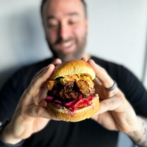 A man holding a vegan burger from Nepenthe