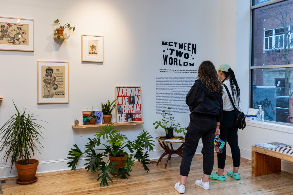 Two women read the description of the new exhibit at NOMU NOMU. The exhibit name is Between Two Worlds.