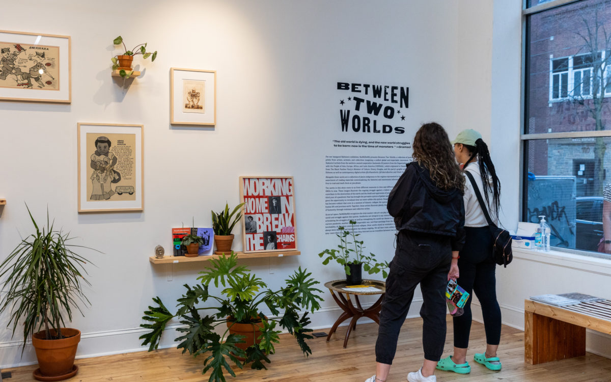 Two women read the description of the new exhibit at NOMU NOMU. The exhibit name is Between Two Worlds.