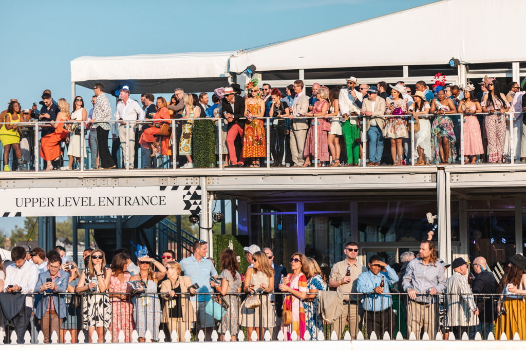 People in colorful outfits watch the Preakness