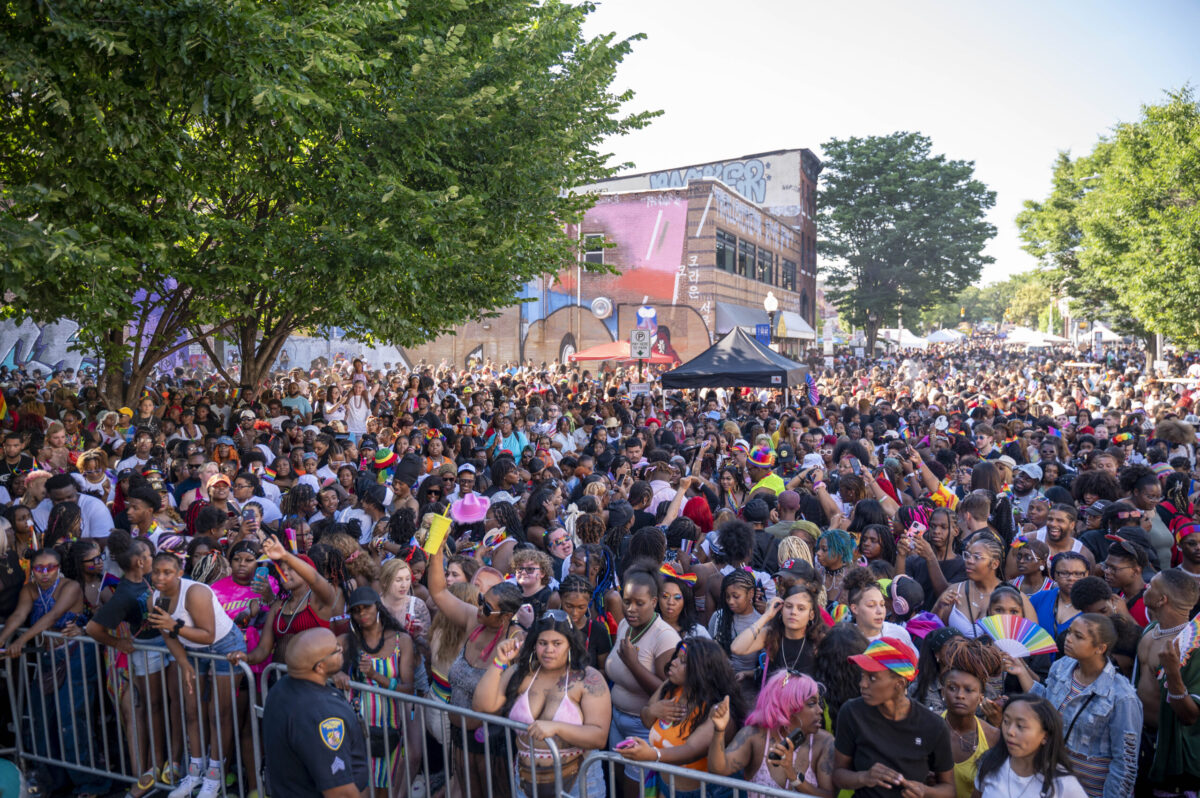 A crowd of people gather behind a fence