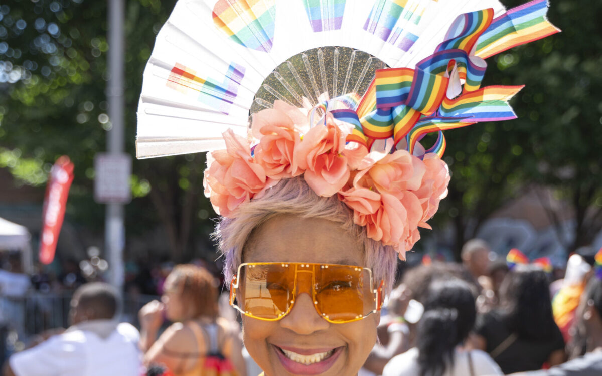 An older woman in a bright orange top wears a head dress that says LOVE