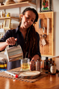 a woman pours wax into a glass container