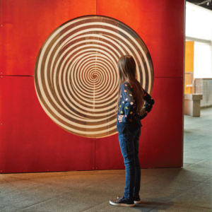 Person in front of a red swirl on the wall at The Maryland Science Center in Baltimore.