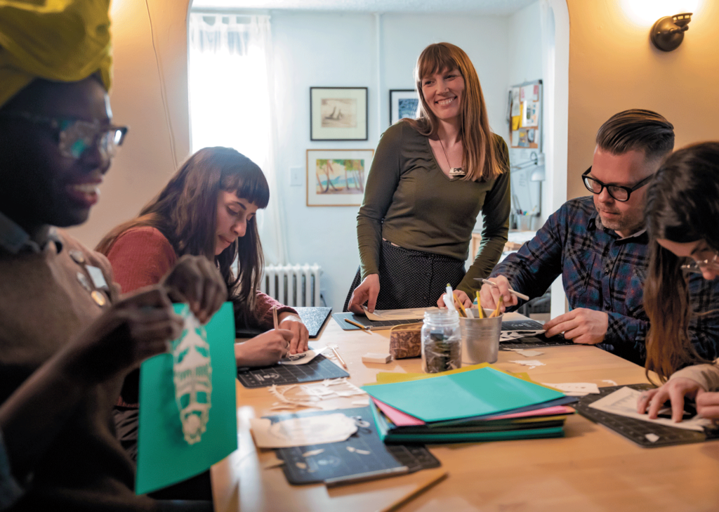 Annie Howe, studio owner, smiles at participants of her paper cutting workshop. 